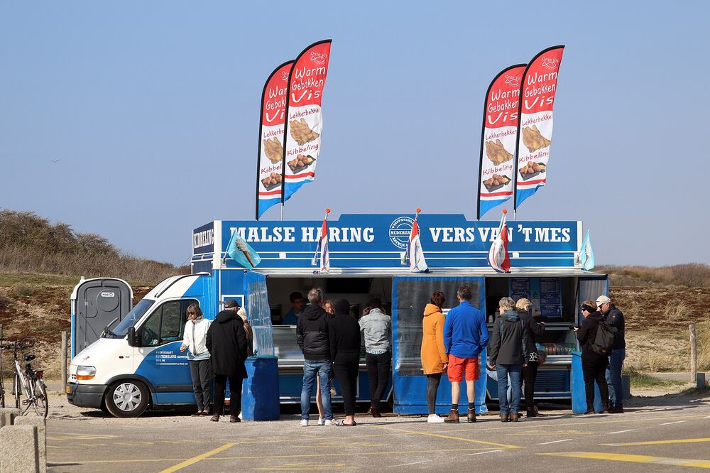 Bezoekers bij een viskraam aan de kust van Katwijk aan Zee